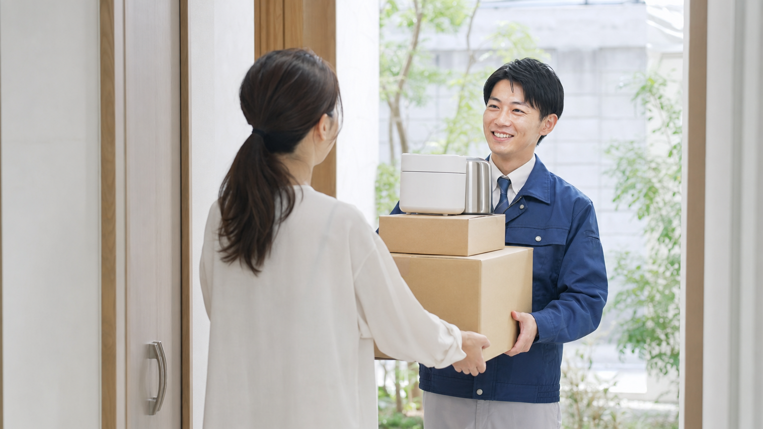 玄関先で、業者スタッフがまとめた品物を受け取る様子